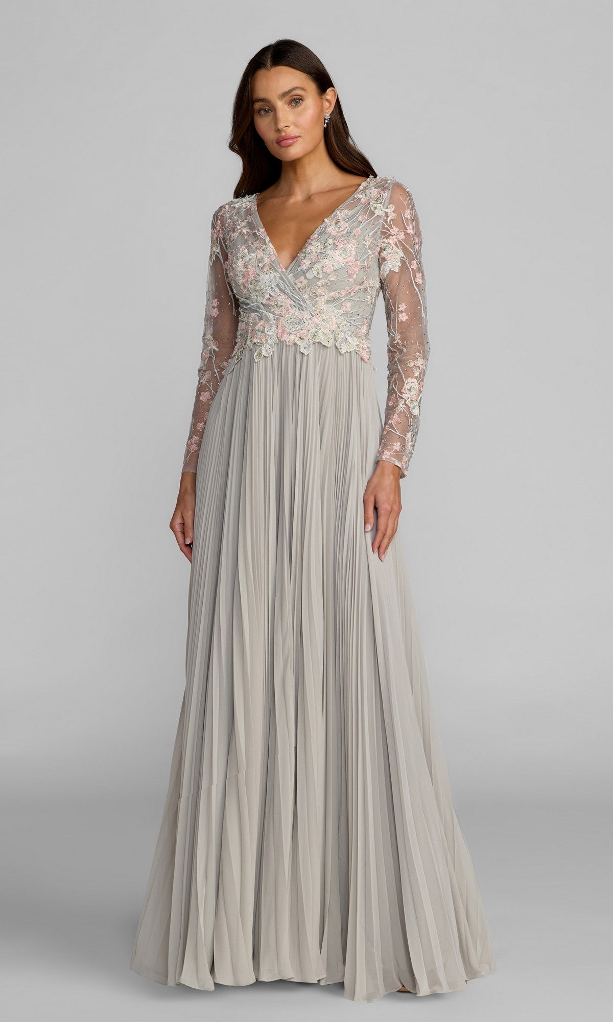 A woman wearing the Mac Duggal 21332 long formal dress in Platinum Multi, featuring a chiffon A-line skirt and sheer, long sleeves adorned with delicate floral embroidery on the bodice and sleeves.